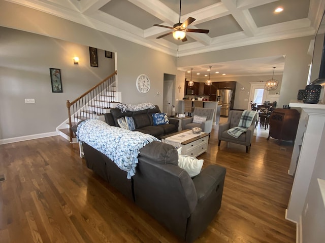 living area featuring ceiling fan with notable chandelier, coffered ceiling, dark wood-style flooring, beamed ceiling, and stairs