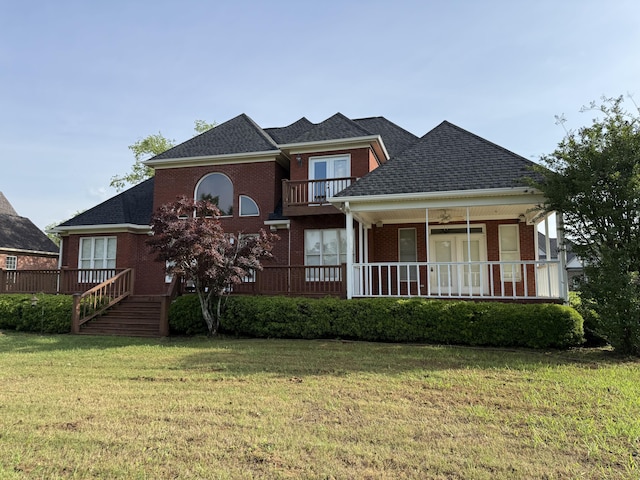 view of front of property featuring a balcony, a shingled roof, brick siding, and a front lawn