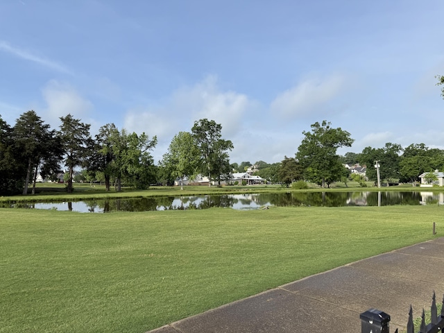 surrounding community with a water view and a lawn