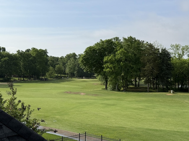 view of home's community featuring fence, golf course view, and a lawn