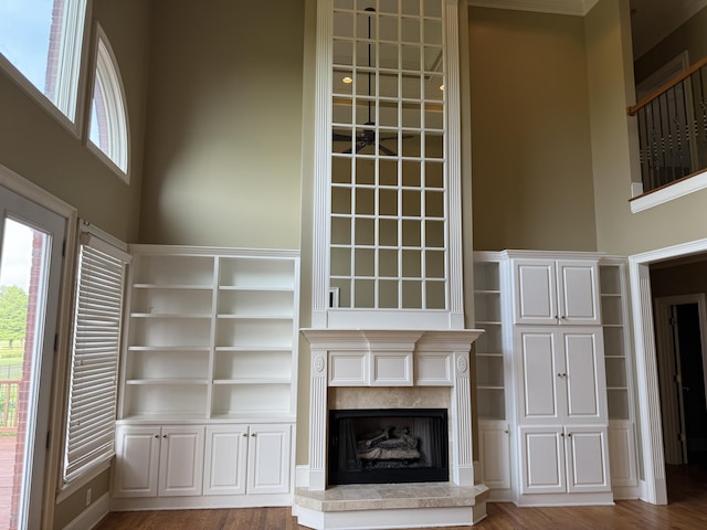 unfurnished living room with wood finished floors, a fireplace with raised hearth, and a high ceiling