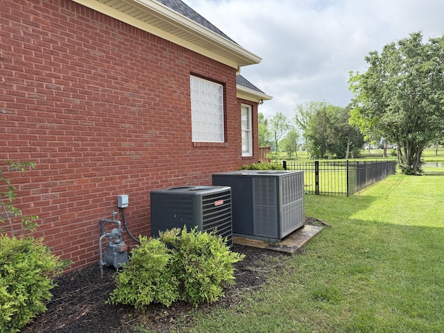 view of property exterior featuring central AC, brick siding, fence, and a lawn
