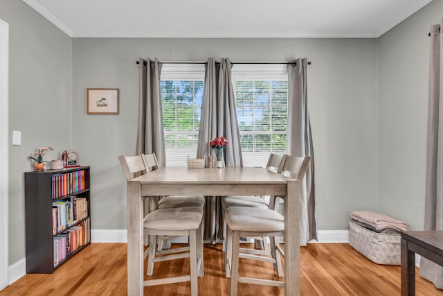 dining space featuring baseboards, ornamental molding, and light wood-style flooring