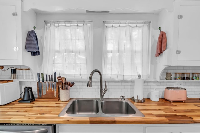 kitchen featuring a sink, backsplash, butcher block countertops, and dishwasher