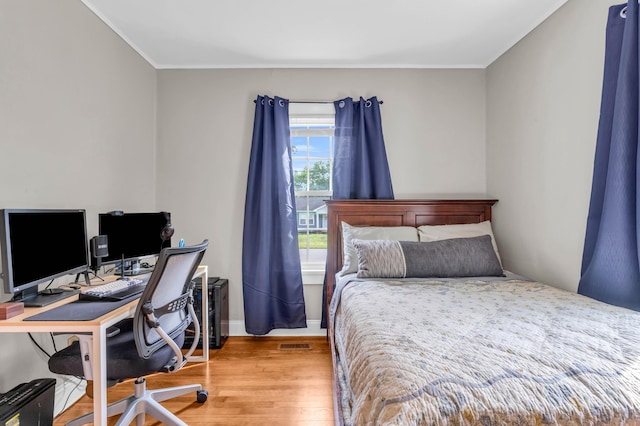 bedroom featuring baseboards, visible vents, ornamental molding, and wood finished floors
