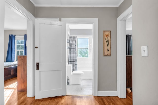 hallway with crown molding, baseboards, and wood finished floors