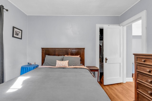 bedroom featuring light wood-type flooring, crown molding, and visible vents