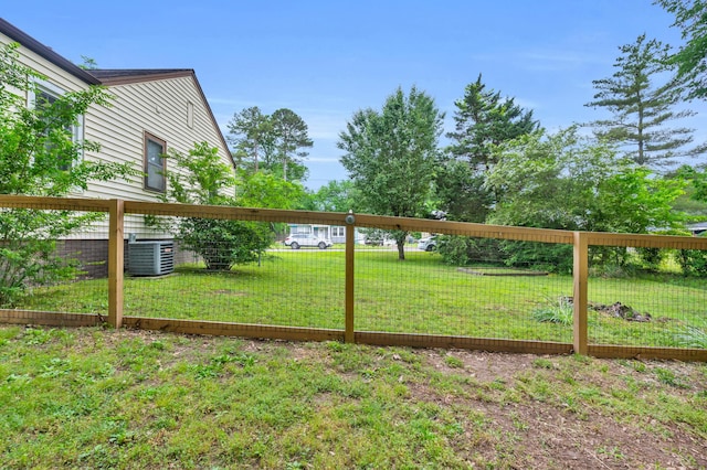 view of yard with central AC and fence