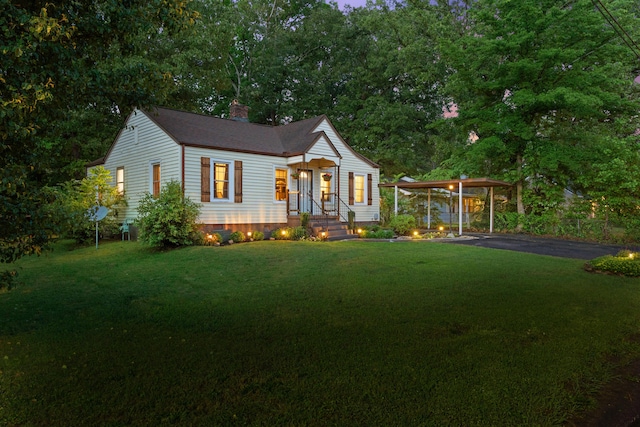 bungalow featuring a carport, a chimney, driveway, and a front lawn