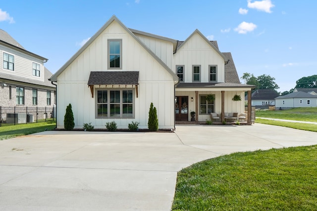 modern inspired farmhouse featuring a front lawn, board and batten siding, and covered porch