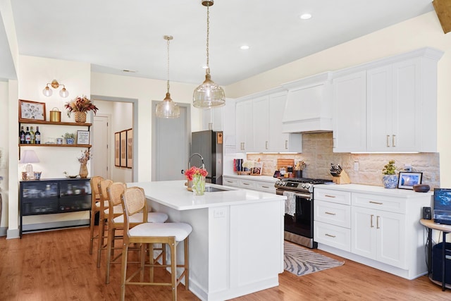 kitchen featuring a breakfast bar area, tasteful backsplash, light countertops, premium range hood, and stainless steel appliances