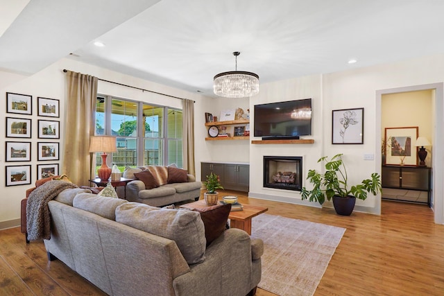 living room featuring recessed lighting, wood finished floors, a notable chandelier, and a fireplace