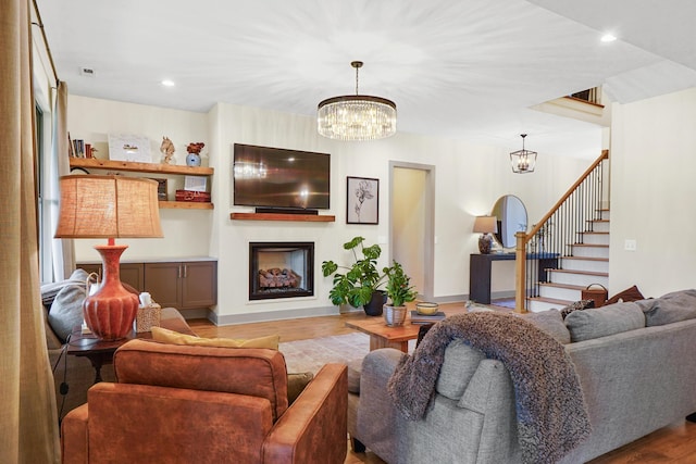 living room featuring wood finished floors, a fireplace, stairway, recessed lighting, and a chandelier