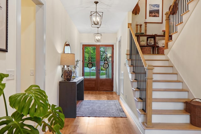 entrance foyer with french doors, stairs, wood finished floors, and a chandelier