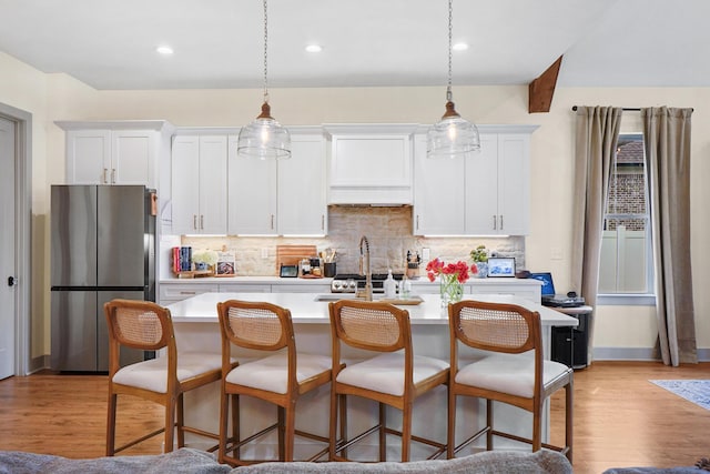 kitchen featuring light countertops, decorative backsplash, freestanding refrigerator, and white cabinetry