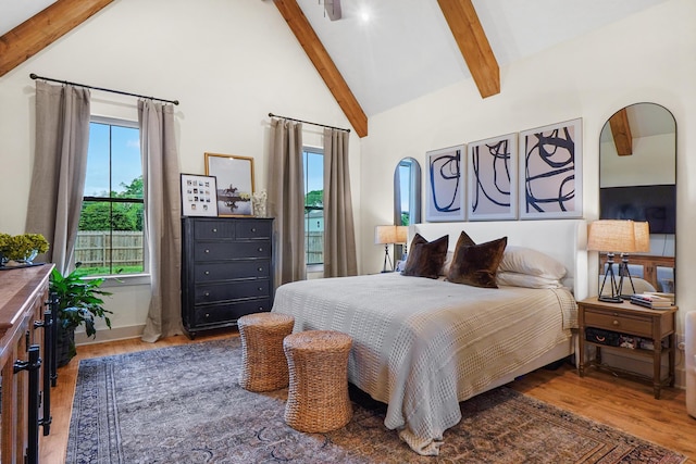 bedroom featuring wood finished floors, high vaulted ceiling, beam ceiling, and multiple windows