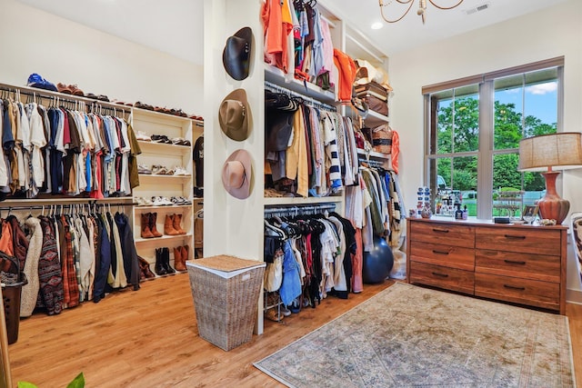 walk in closet with a chandelier, wood finished floors, and visible vents