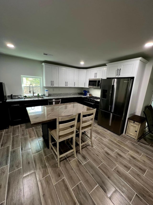 5561 River Rd, Decatur, TN 37322 - kitchen featuring appliances with stainless steel finishes, wood tiled floors, white cabinetry, recessed lighting, and a sink