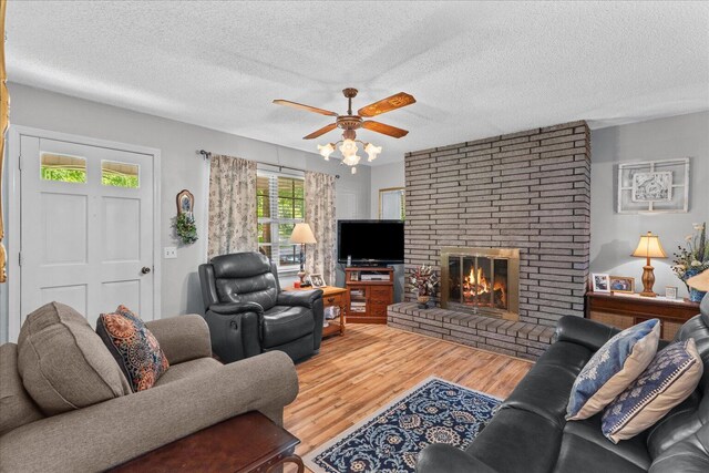 4042 Village Dr, Cohutta, GA 30710 - living area with a textured ceiling, wood finished floors, a ceiling fan, and a brick fireplace