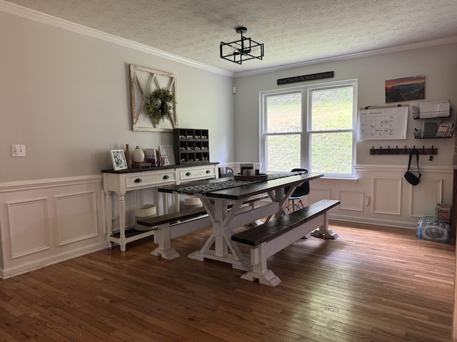 dining room featuring crown molding, a decorative wall, wainscoting, and hardwood / wood-style floors