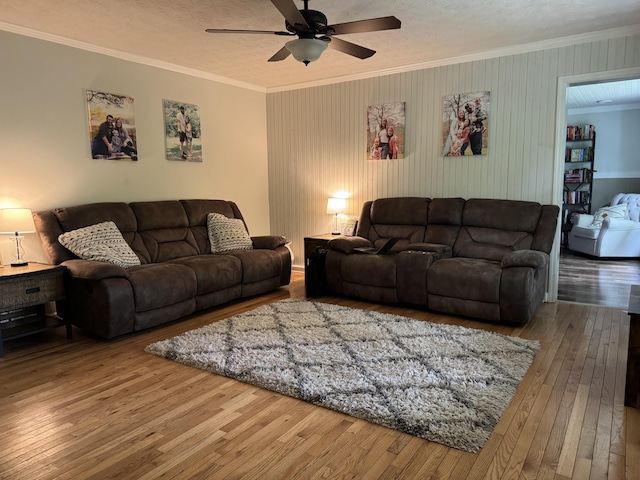 living room featuring crown molding, wood-type flooring, and ceiling fan