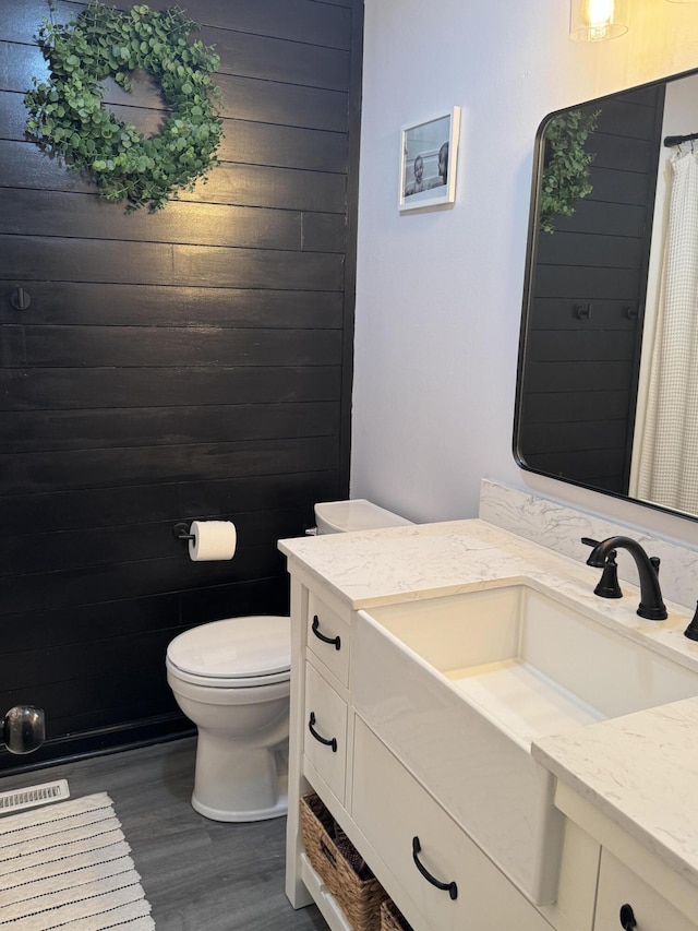 bathroom with toilet, curtained shower, vanity, and wood finished floors