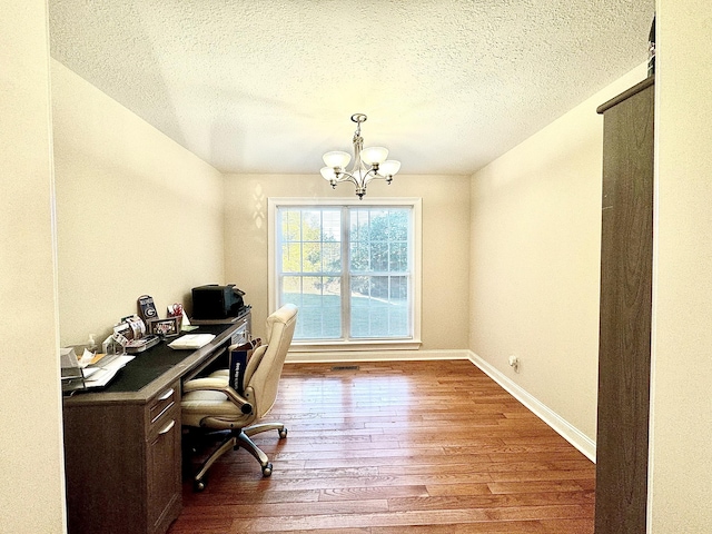 office space featuring an inviting chandelier, a textured ceiling, baseboards, and wood finished floors