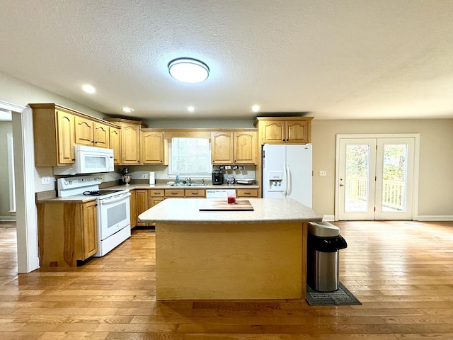 kitchen featuring a sink, white appliances, light wood-type flooring, light countertops, and a kitchen island