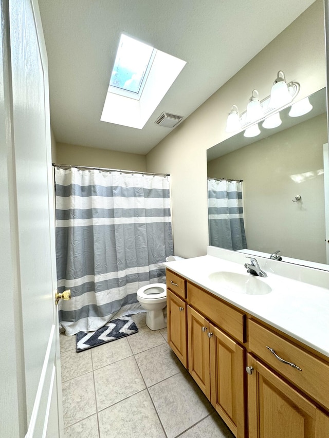 full bathroom with toilet, visible vents, tile patterned floors, vanity, and a skylight