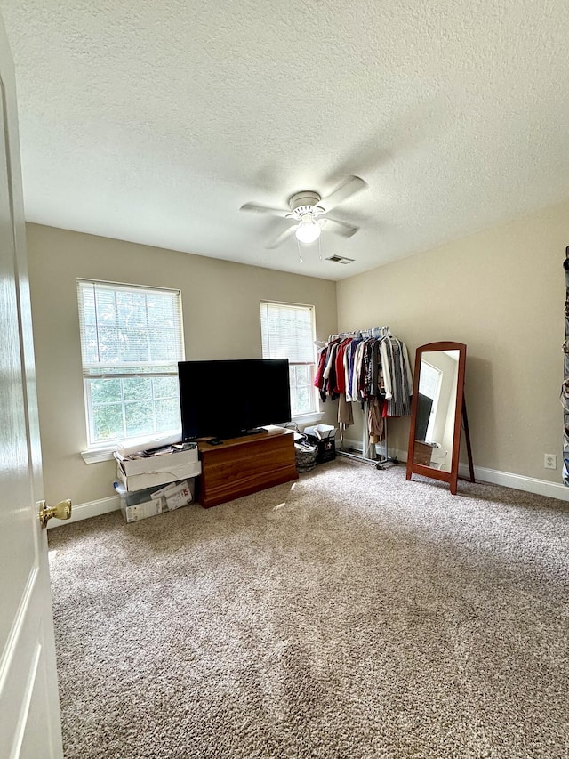 carpeted bedroom featuring a textured ceiling, baseboards, and a ceiling fan