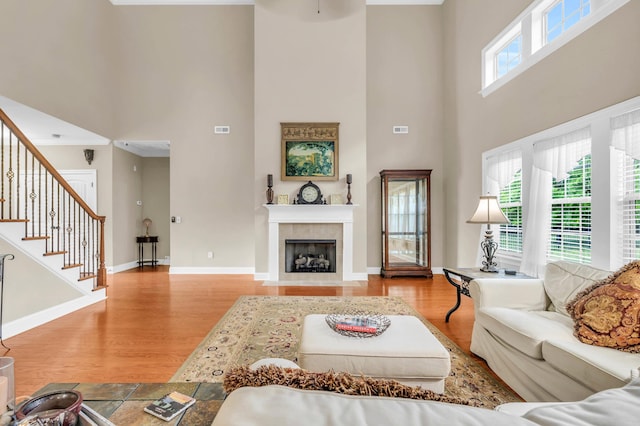 8358 Front Gate Cir, Ooltewah, TN 37363 - living room with a towering ceiling, wood finished floors, stairway, a tile fireplace, and baseboards