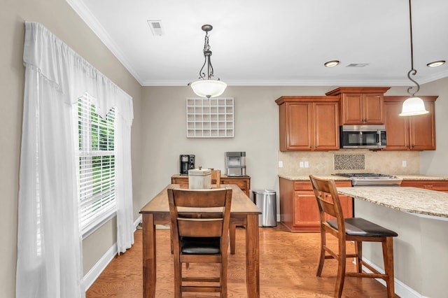 8358 Front Gate Cir, Ooltewah, TN 37363 - kitchen featuring stainless steel microwave, ornamental molding, tasteful backsplash, light wood-type flooring, and brown cabinets