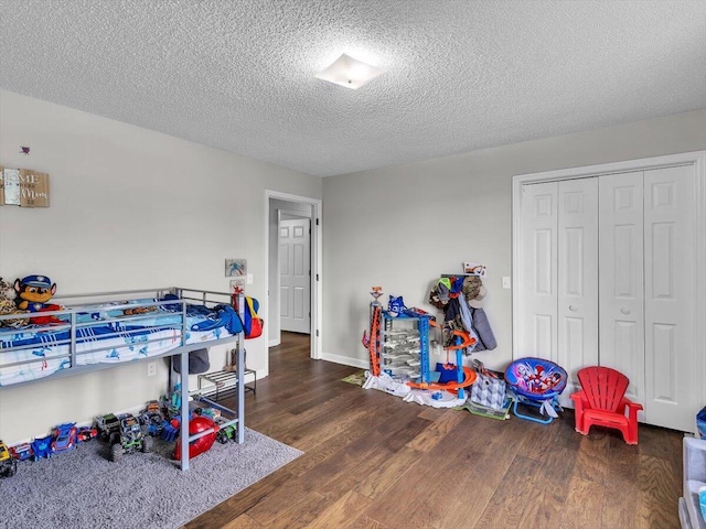 bedroom featuring wood finished floors, a textured ceiling, a closet, and baseboards