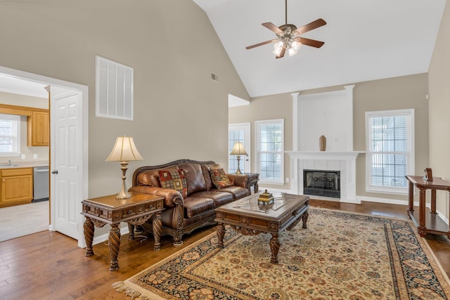 living room featuring dark wood-style flooring, ceiling fan, visible vents, and high vaulted ceiling