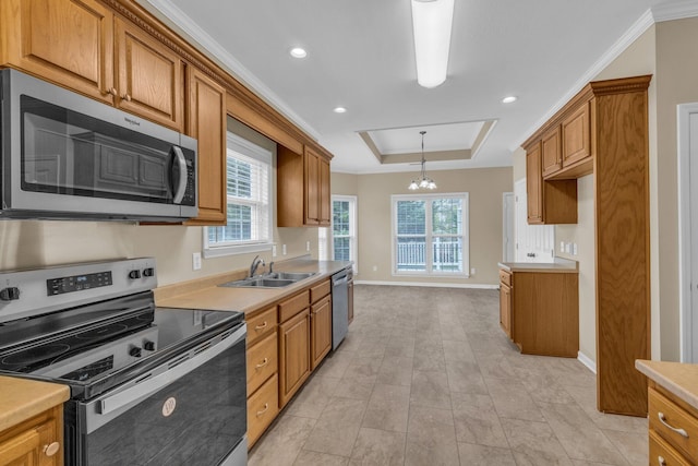 kitchen with a sink, brown cabinetry, light countertops, appliances with stainless steel finishes, and a chandelier