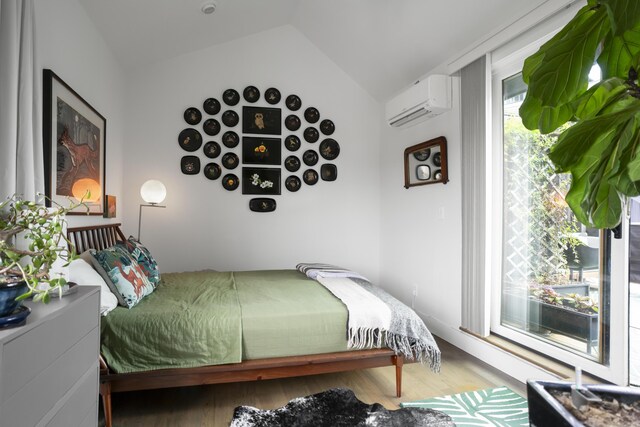 bedroom featuring a wall mounted air conditioner, lofted ceiling, and wood finished floors