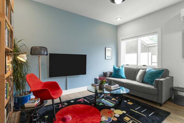 living room featuring wood finished floors, a wall unit AC, and recessed lighting