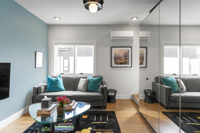 living room featuring a wall mounted AC, baseboards, and light wood-style floors