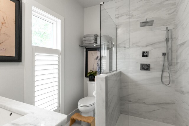 bathroom with a marble finish shower, toilet, and vanity