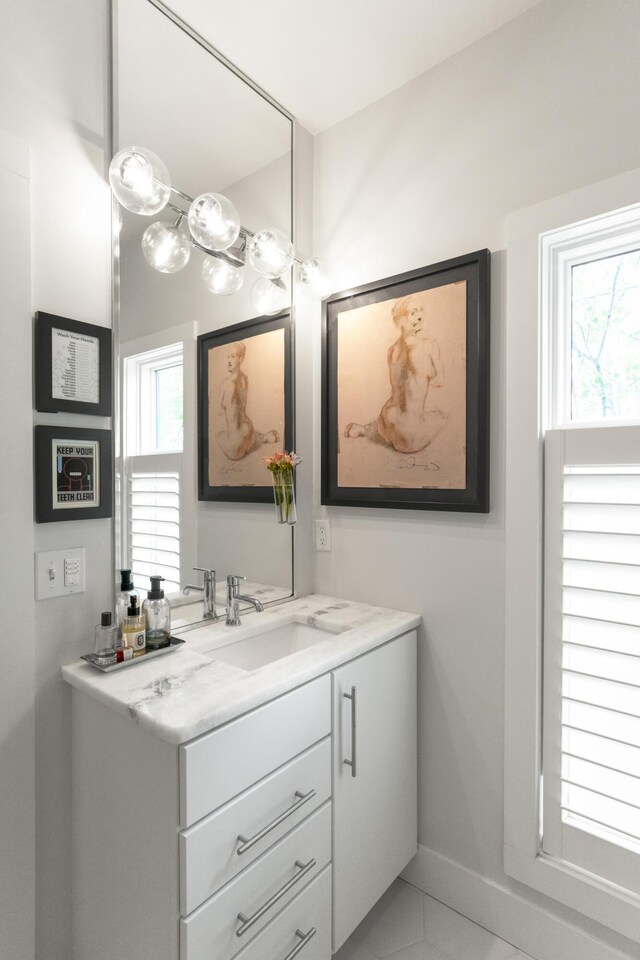bathroom featuring healthy amount of natural light, vanity, tile patterned flooring, and baseboards