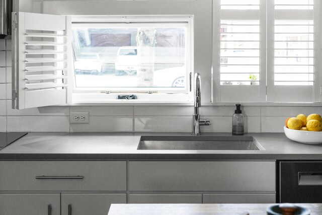 kitchen with a sink, dishwashing machine, and tasteful backsplash