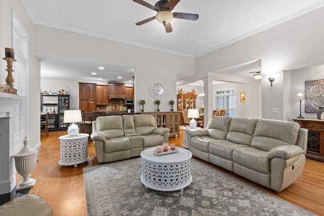 212 Smith St, Signal Mountain, TN 37377 - living room featuring decorative columns, a ceiling fan, light wood finished floors, crown molding, and a fireplace with raised hearth