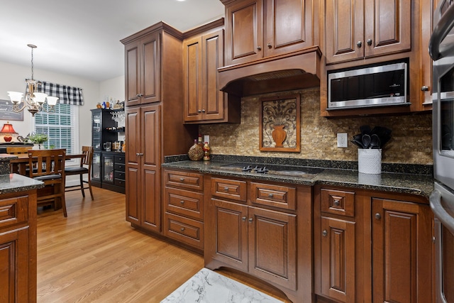 212 Smith St, Signal Mountain, TN 37377 - kitchen featuring stainless steel microwave, under cabinet range hood, light wood finished floors, decorative backsplash, and a chandelier