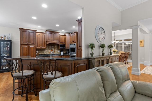 212 Smith St, Signal Mountain, TN 37377 - kitchen with appliances with stainless steel finishes, a breakfast bar, crown molding, backsplash, and light wood-type flooring