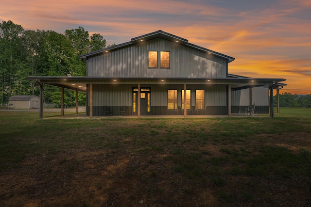 back of property at dusk featuring a yard, a shed, and an outbuilding