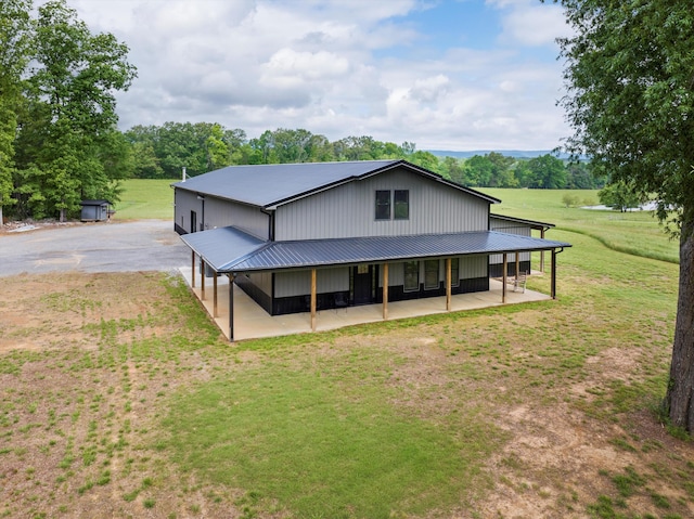 back of house featuring metal roof, a yard, and a patio