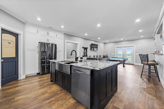 kitchen with stainless steel appliances, a sink, a kitchen island with sink, french doors, and white cabinets