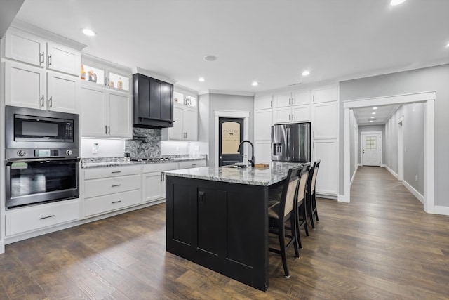 kitchen with appliances with stainless steel finishes, a sink, tasteful backsplash, glass insert cabinets, and recessed lighting