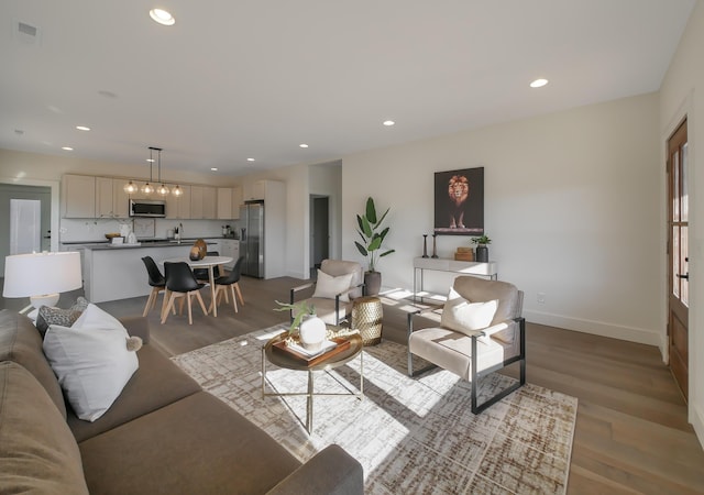 living room with light wood finished floors, baseboards, visible vents, and recessed lighting