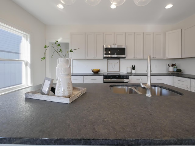 kitchen with a sink, recessed lighting, dark countertops, and appliances with stainless steel finishes